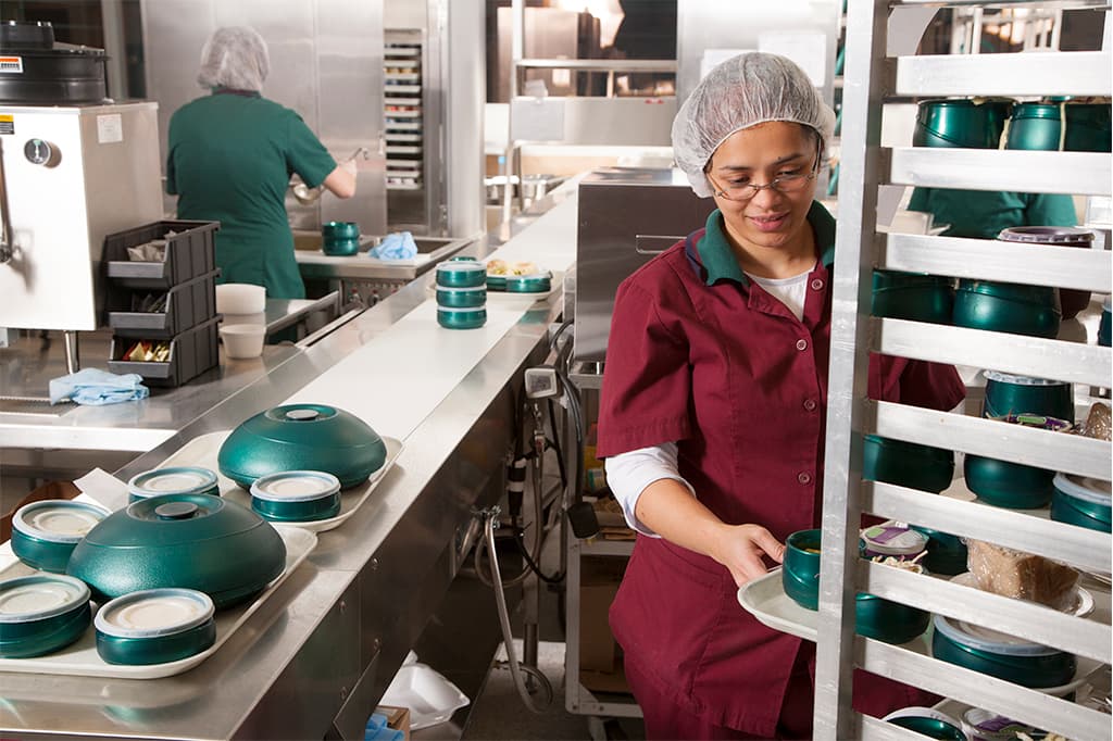 Food worker in commercial kitchen preparing meal